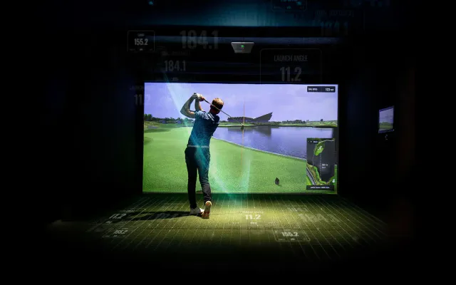 Golfer mid-swing in a finished golf simulator