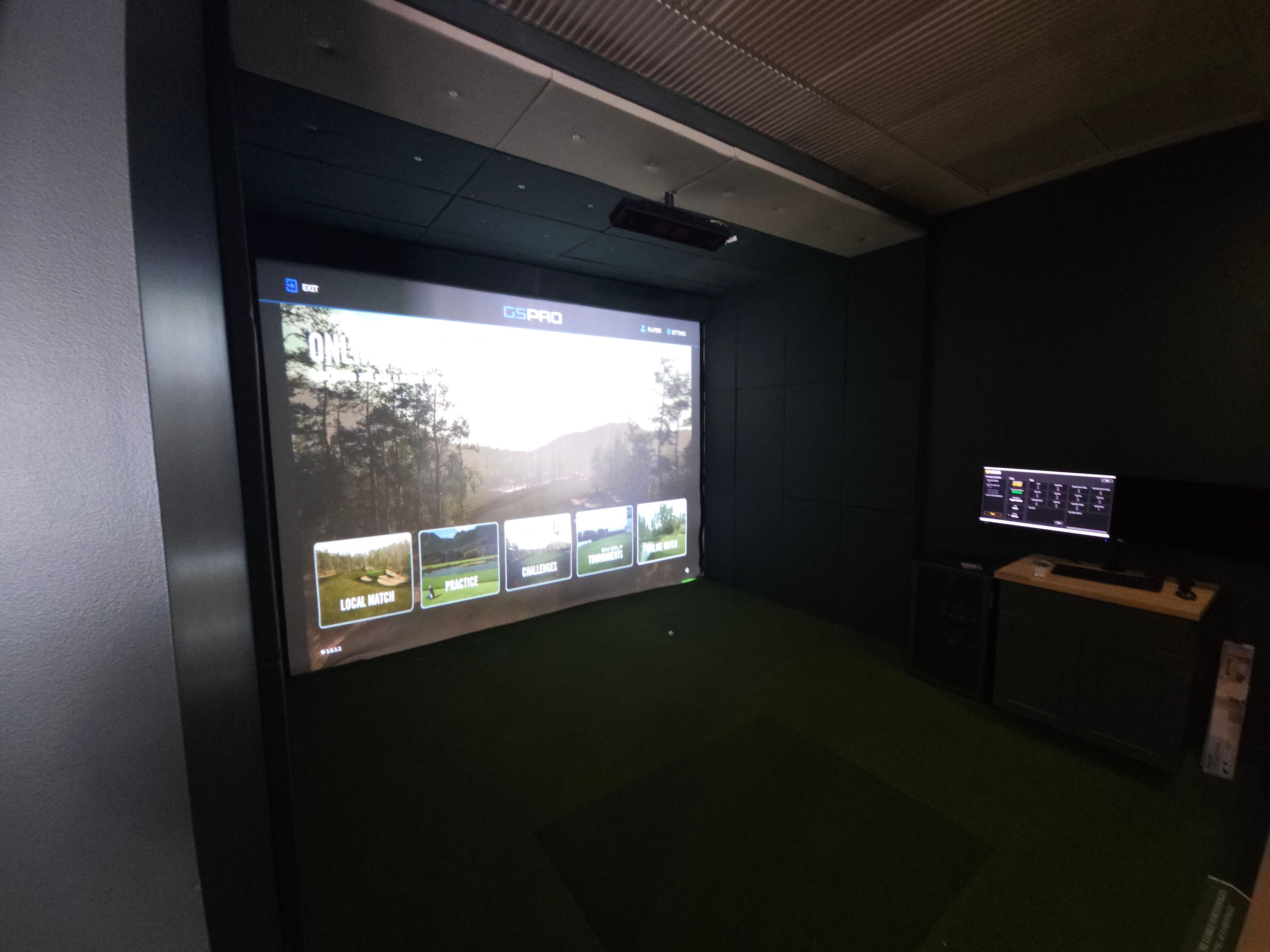 Finished simulator bay at All Seasons Indoor Golf Club with GSPro on a wall-to-wall impact screen