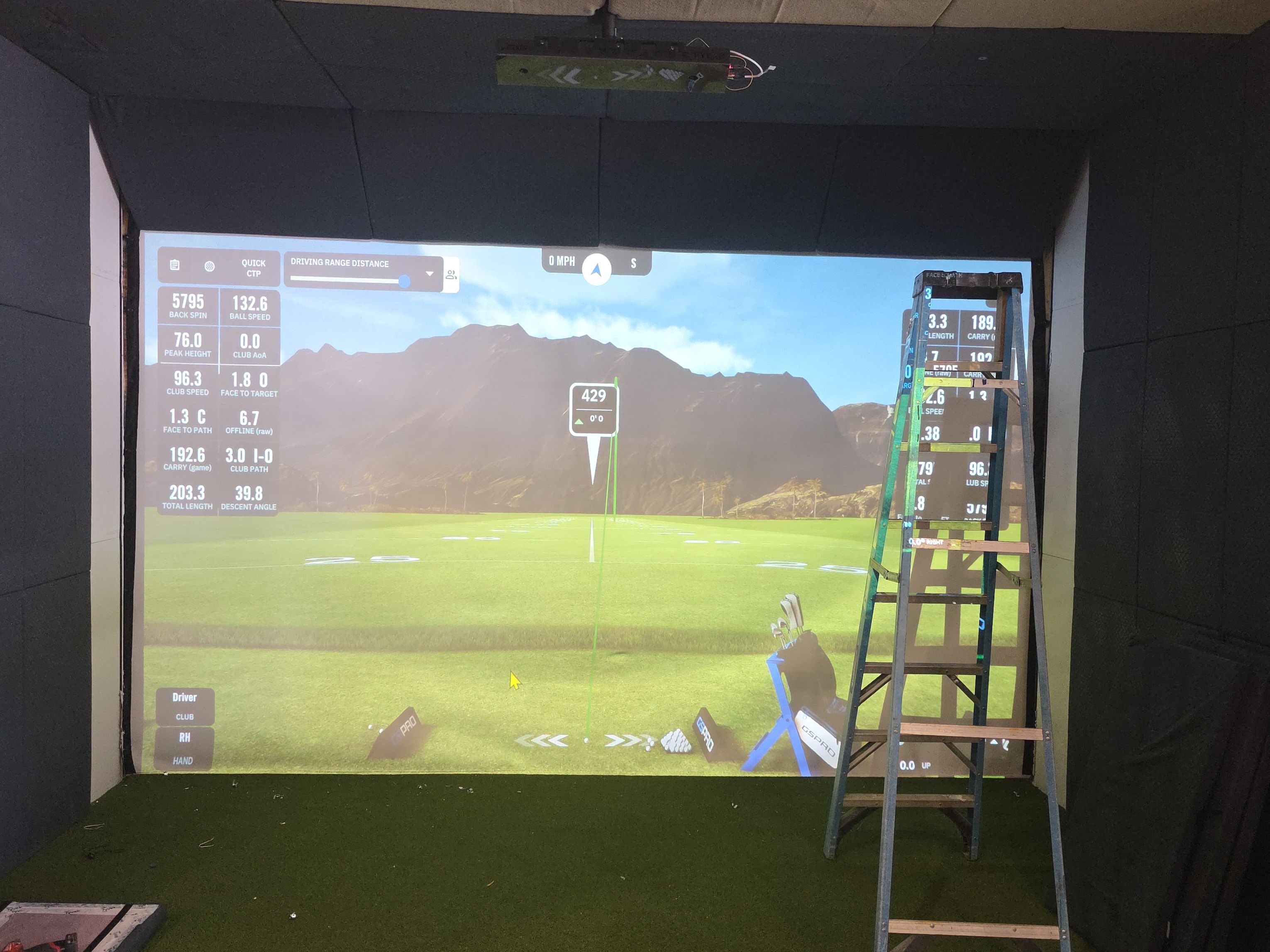 A simulator bay being finished and calibrated at All Seasons Indoor Golf Club, screen up with a ladder in place