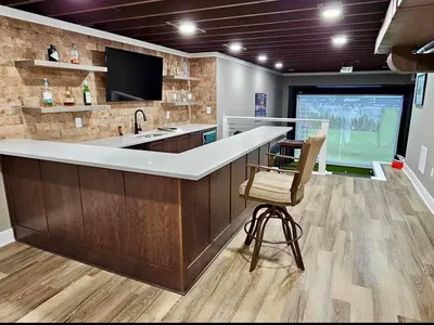 Custom basement bar and millwork beside a finished golf simulator bay
