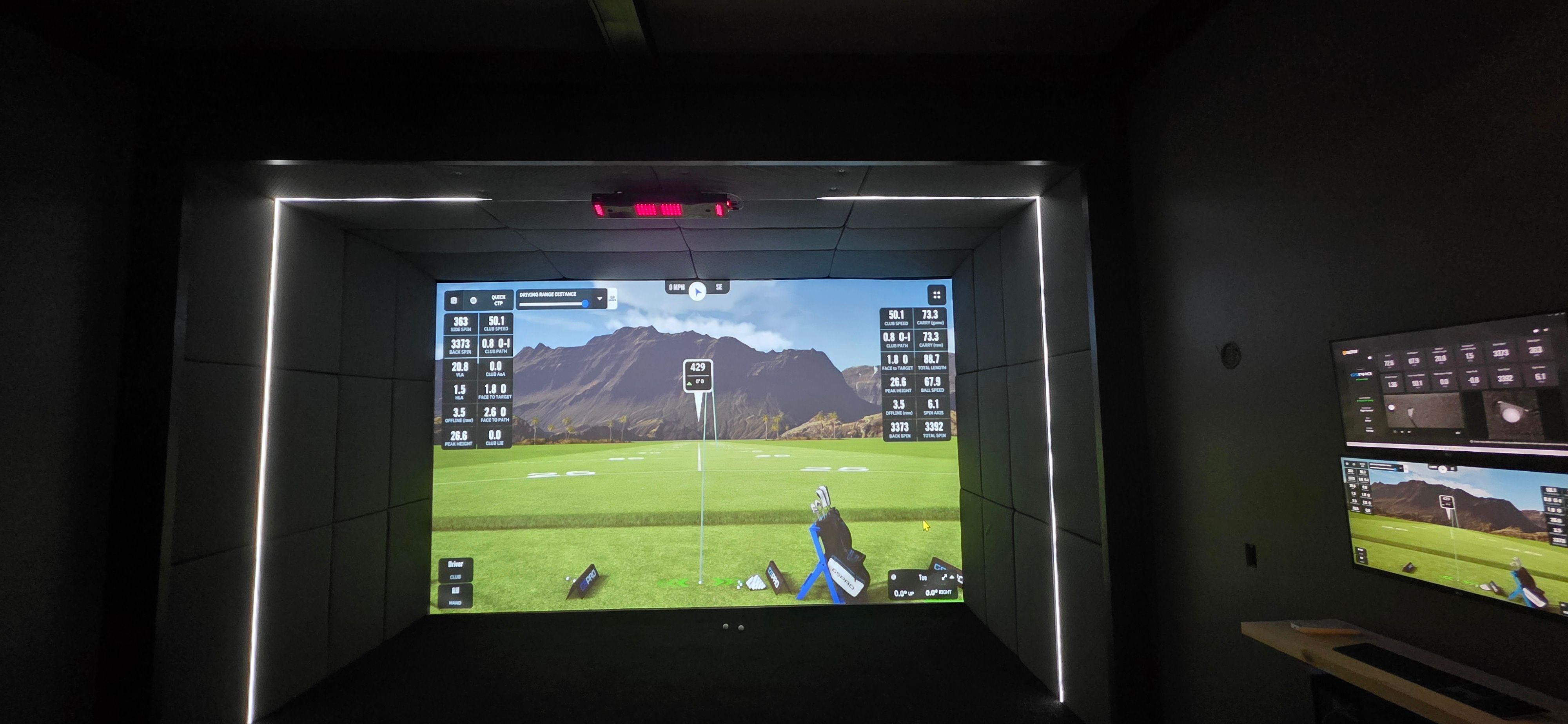 Finished basement golf simulator in the Grain Valley home with GSPro on screen and LED lighting over the hitting area