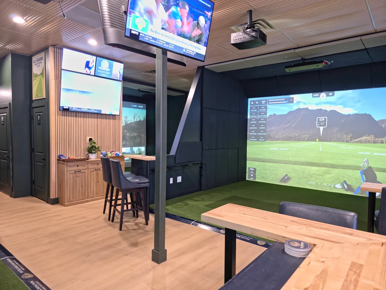 Finished indoor golf simulator installation with lounge seating and a course on the screen