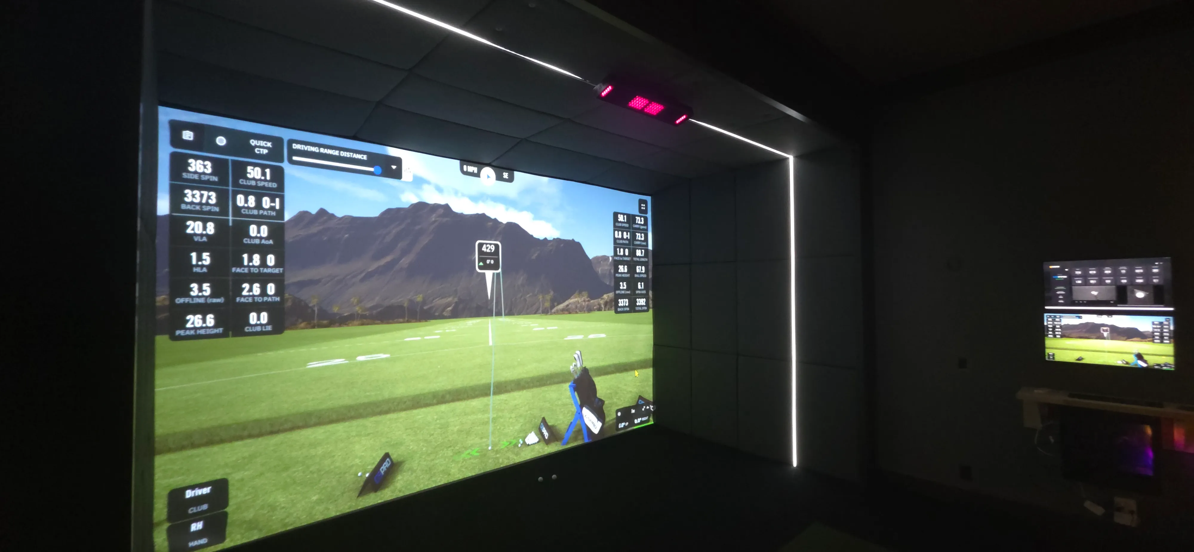 Finished golf simulator bay with launch-monitor shot data on the impact screen and LED-lit walls — a build like those All Seasons creates for Lake of the Ozarks homes, shown at the Kansas City showroom
