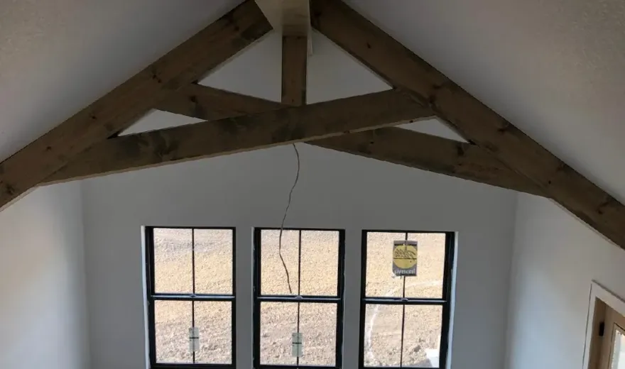 Vaulted room with exposed timber truss beams during a custom golf simulator buildout