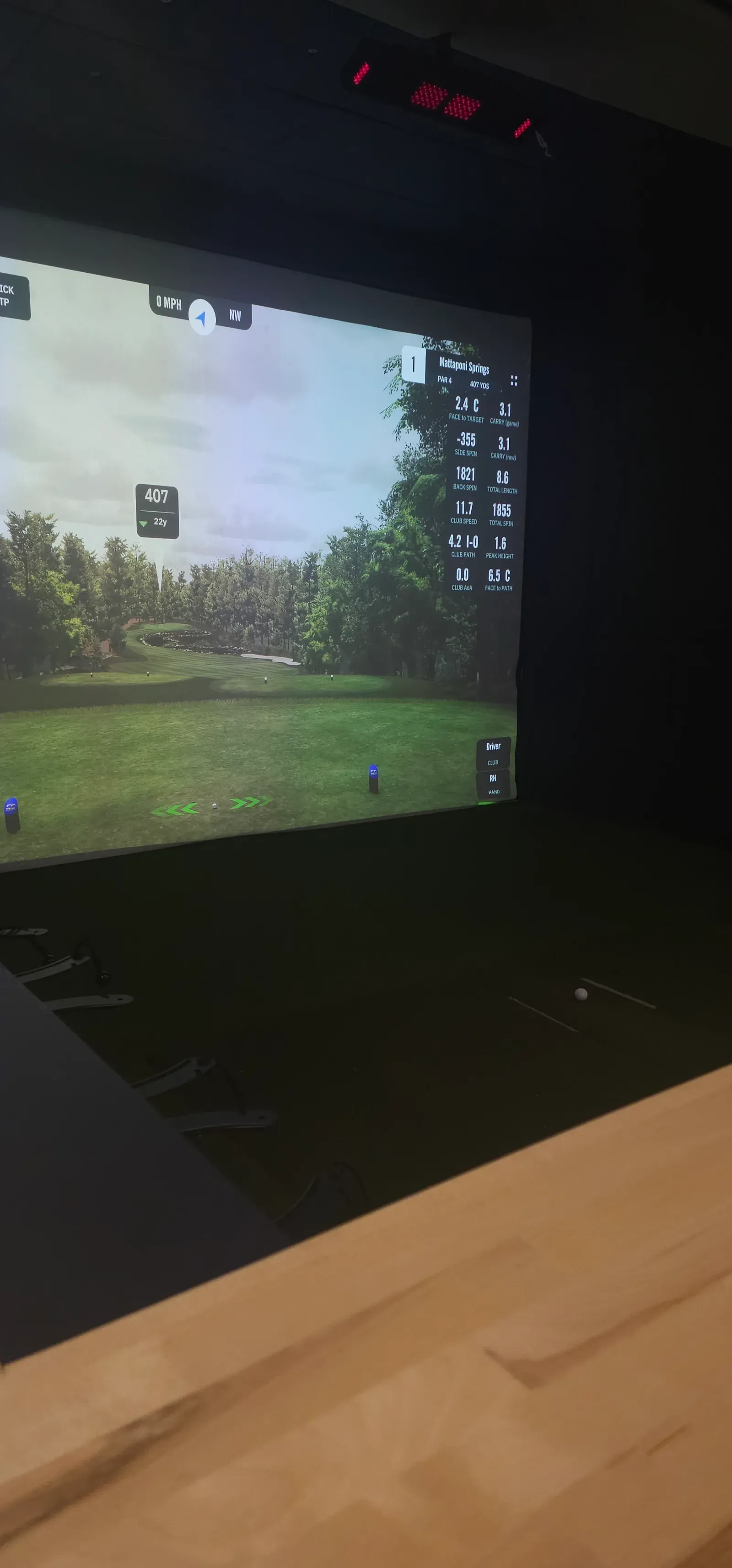 Golf simulator screen with live shot data and an overhead launch monitor in a finished custom build