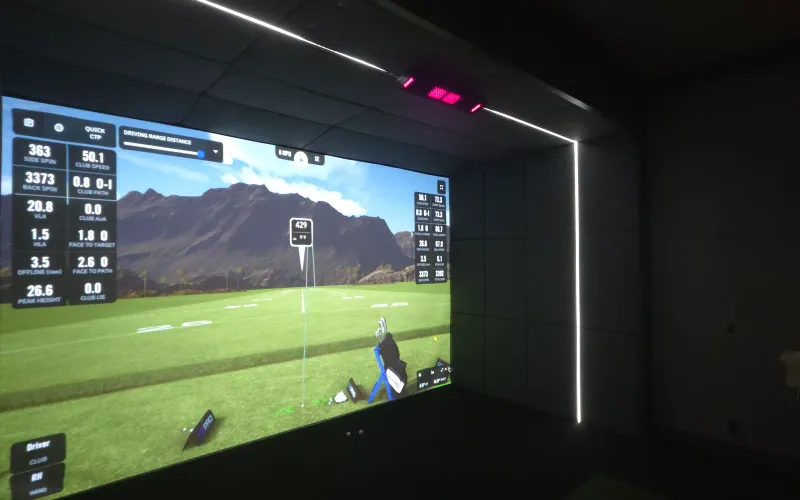 Calibrated golf simulator bay with a shot-data overlay and an overhead launch monitor