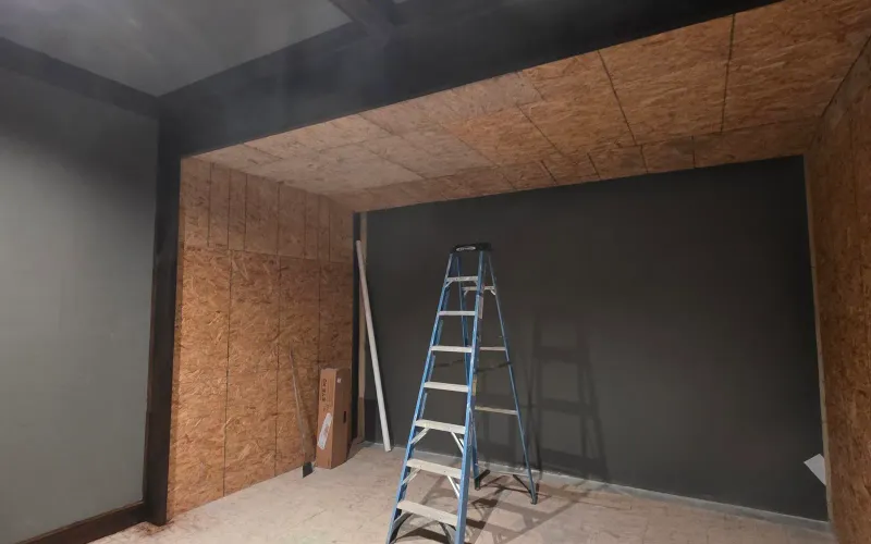Golf simulator bay under construction with OSB-sheathed walls and ceiling