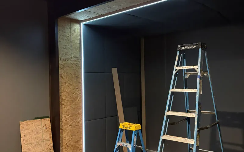 Golf simulator enclosure under professional installation with an LED-lit frame and acoustic panels