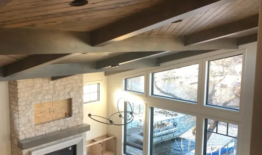 Finished room with a vaulted wood-beam ceiling and lake-view windows for a home golf simulator